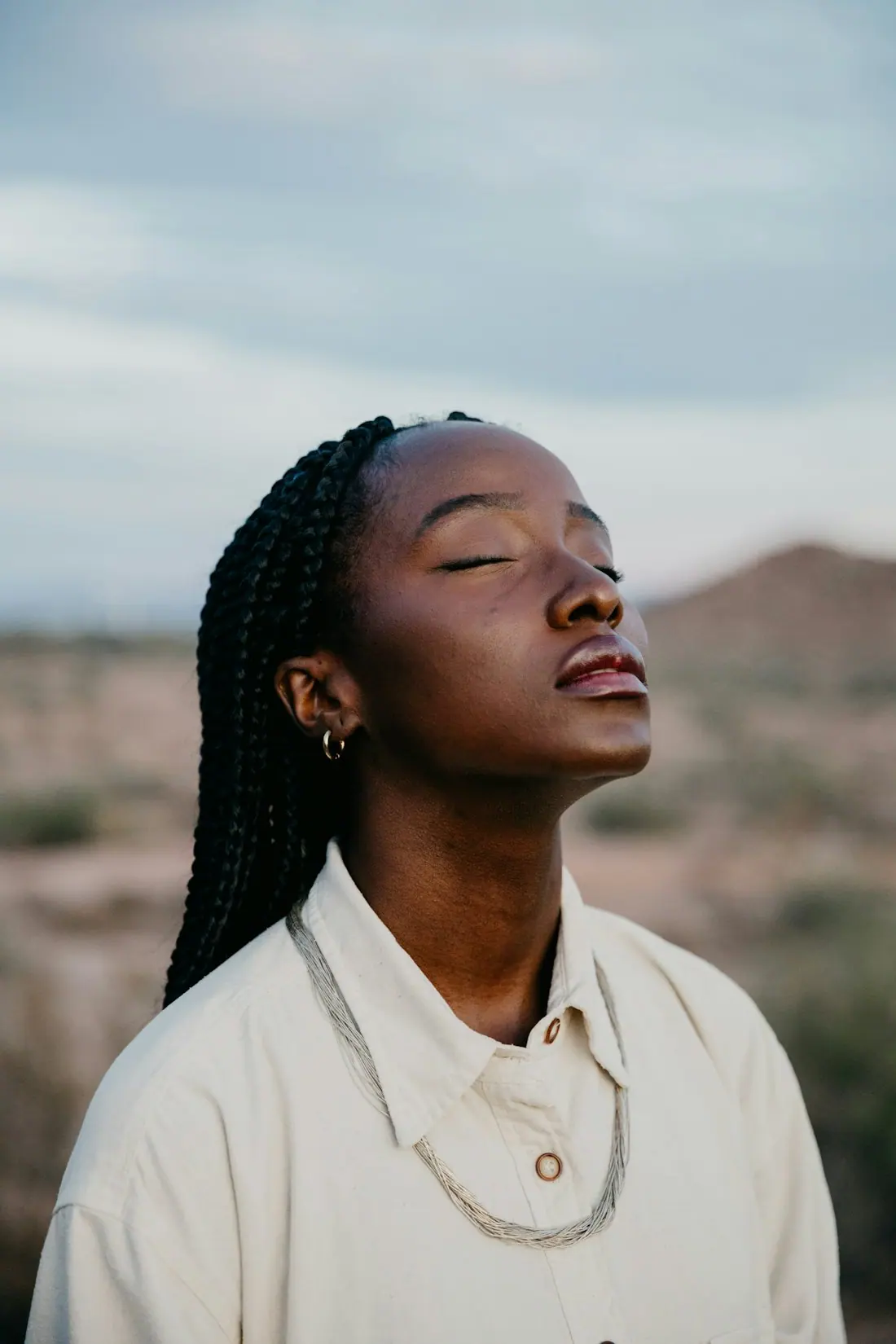 A person breathing quietly with eyes closed outdoors